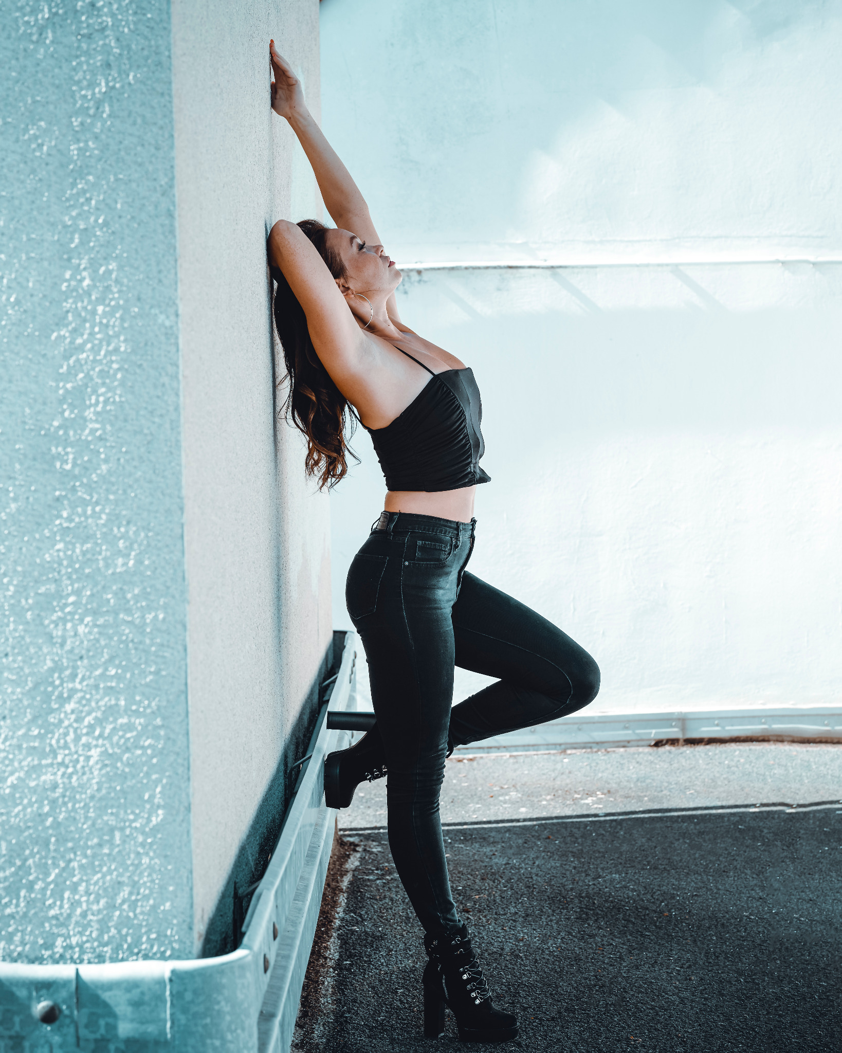 Frau in schwarzem Outfit an einer hellen Wand