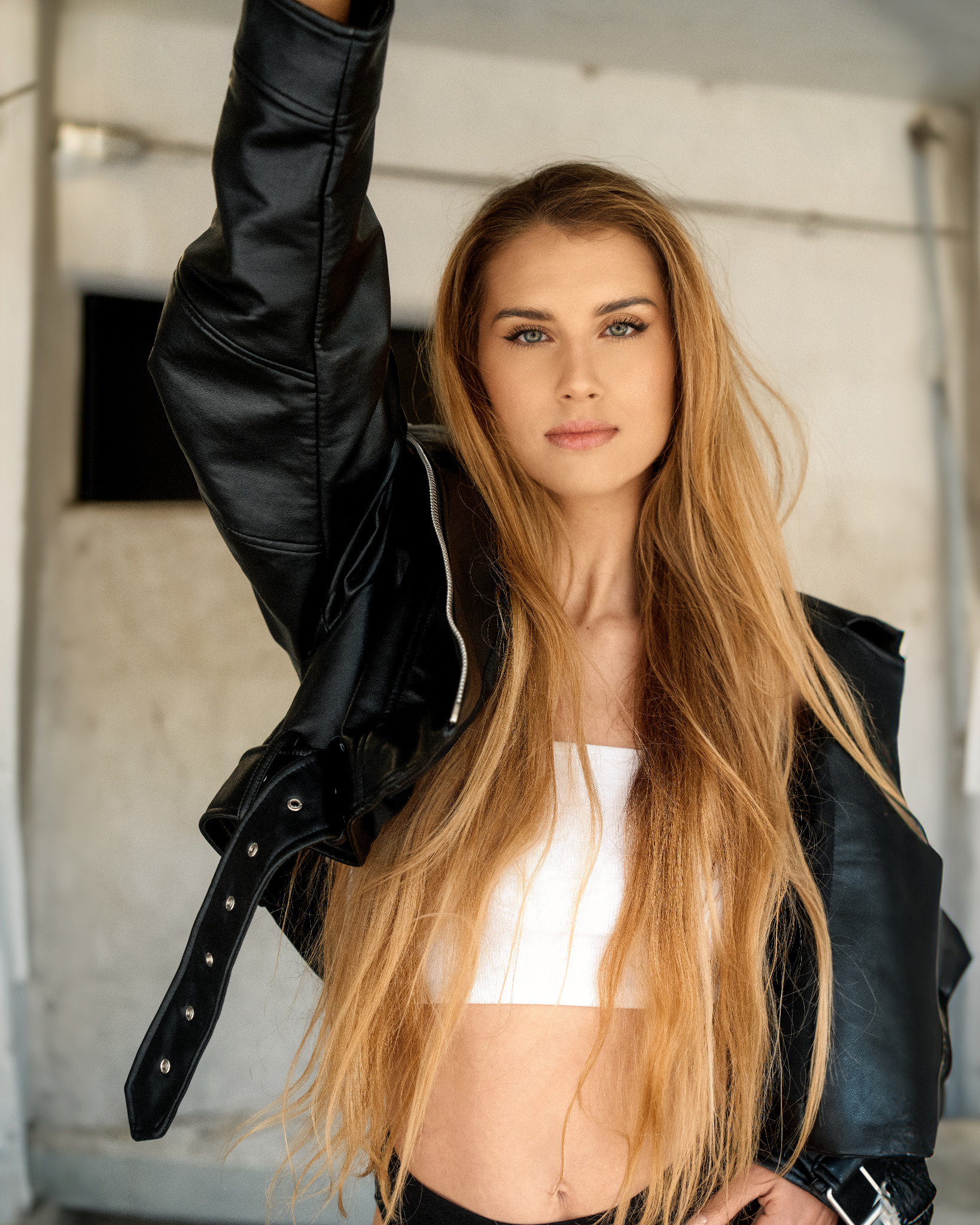 Portrait einer Frau mit erhobenem Arm in schwarzer Jacke