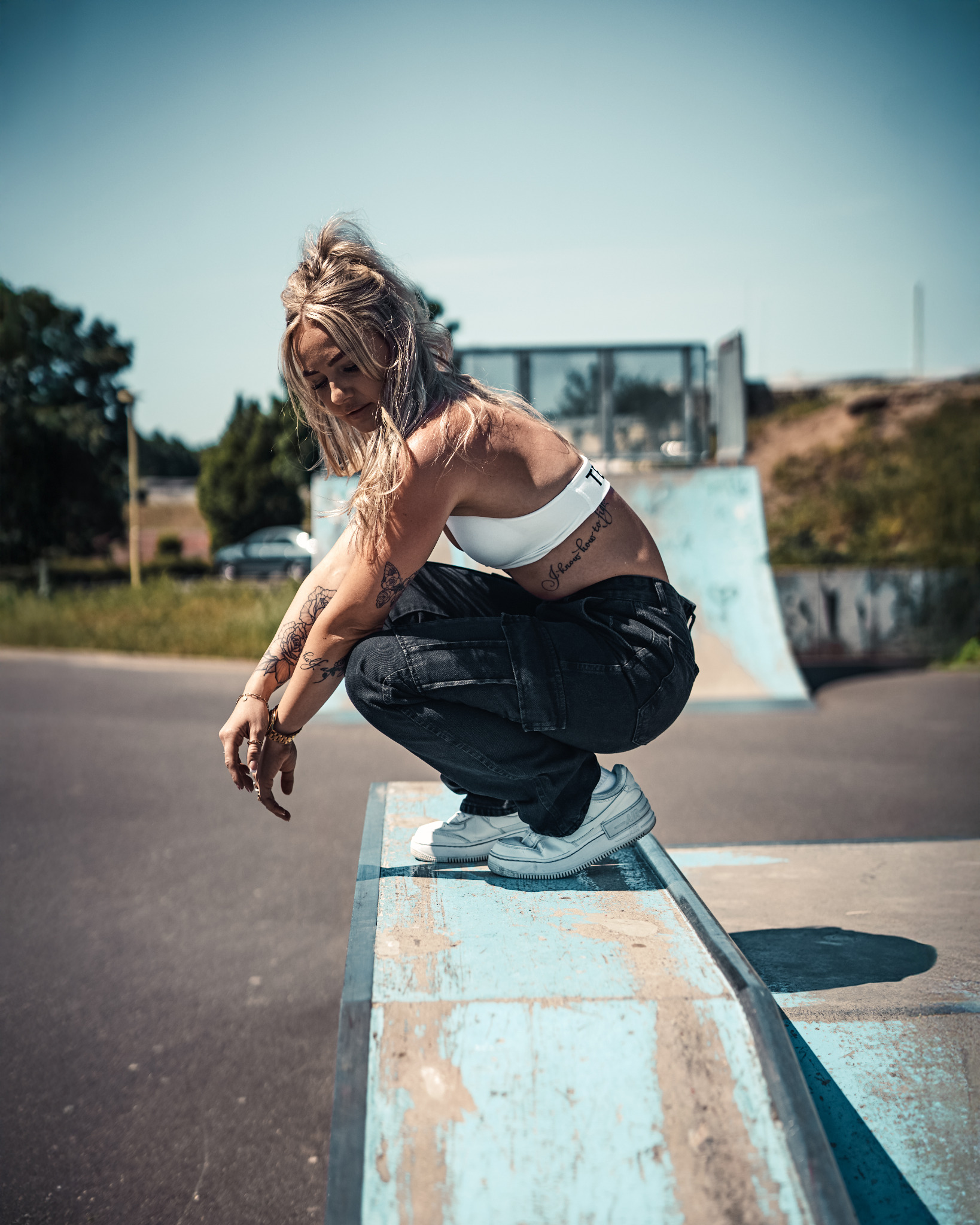 Modeaufnahme einer Frau in der Hocke auf einem Skate-Element
